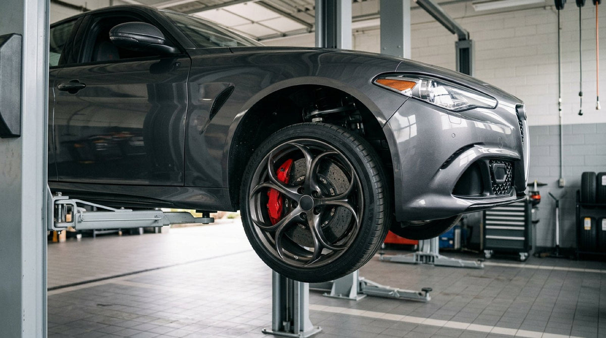 Alfa Romeo Giulia wheel well showing carbon ceramic brake rotor and multi-piston caliper clearance behind 19-inch wheel