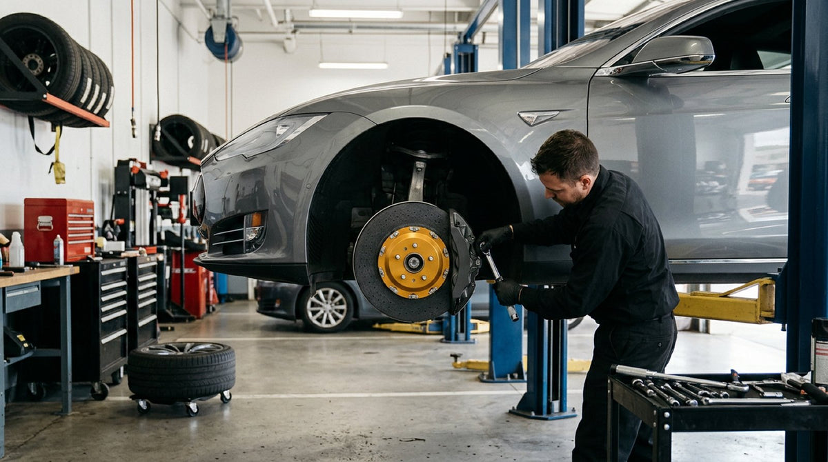 Front carbon ceramic brake rotor and caliper assembly on a Tesla Model S in a workshop, illustrating Tesla carbon ceramic rot