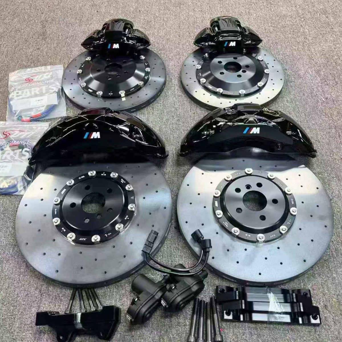 Complete plug-and-play ForzaCCB carbon ceramic big brake kit for BMW M, featuring black M calipers, four rotors, EPB motors, braided lines, and mounting brackets.